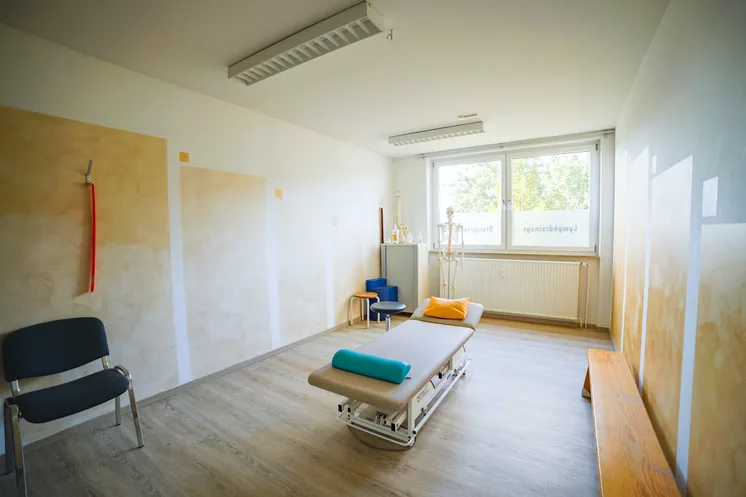 Behandlungsraum mit Liege, Skelettmodell und Fensterfront