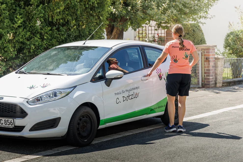 Physiotherapeutin am Praxisauto der Praxis Dotzler für Hausbesuche