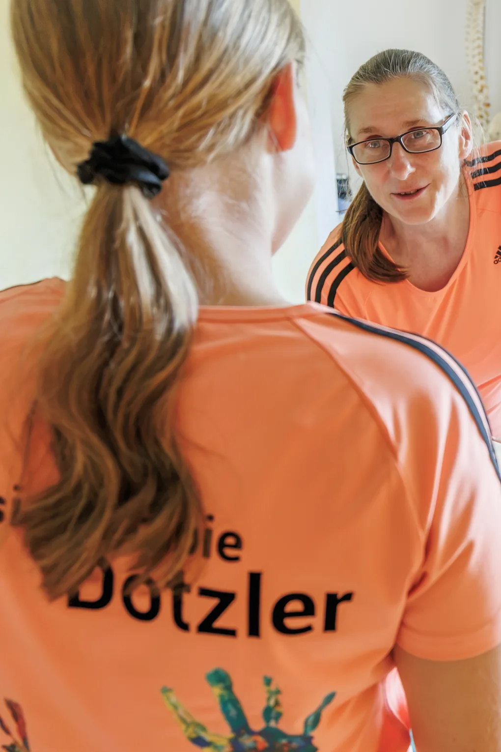 Zwei Therapeutinnen der Praxis Dotzler im Gespräch, eine im Team-Shirt mit Praxisschriftzug