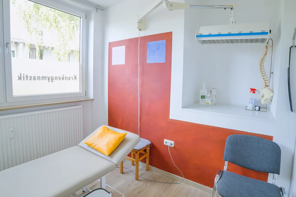 Behandlungsraum mit Liege und Wärmestrahler am Schwenkarm